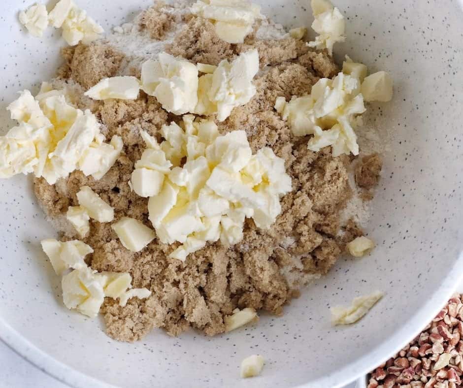 A baking dish lined with parchment paper, set aside for preparing Air Fryer Maple Pecan Bars, with small cubes of cold butter and dry ingredients ready to be mixed.