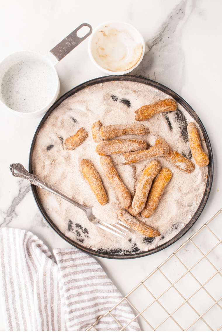 Easy Air Fryer Pumpkin Churros coated in cinnamon sugar with a frosting dip
