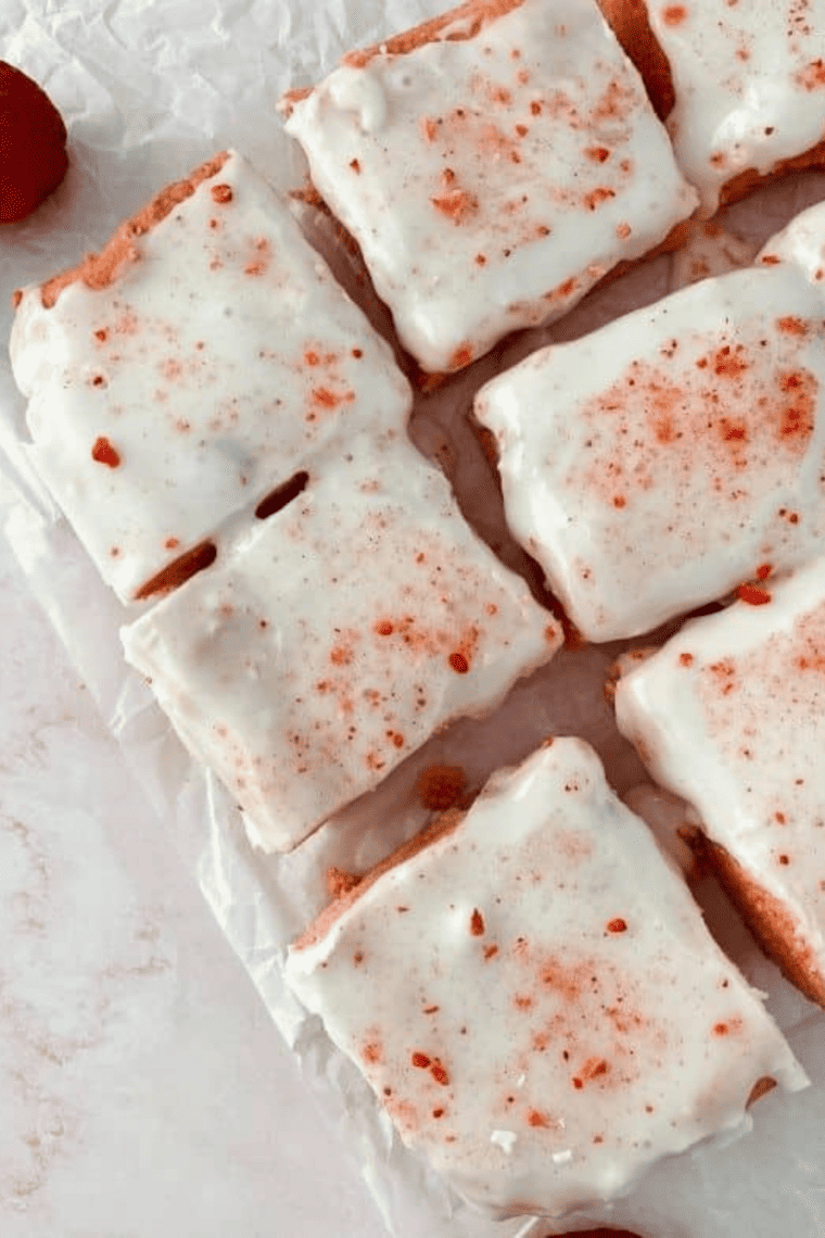 Glazed air fryer strawberry blondies cut into squares on parchment paper