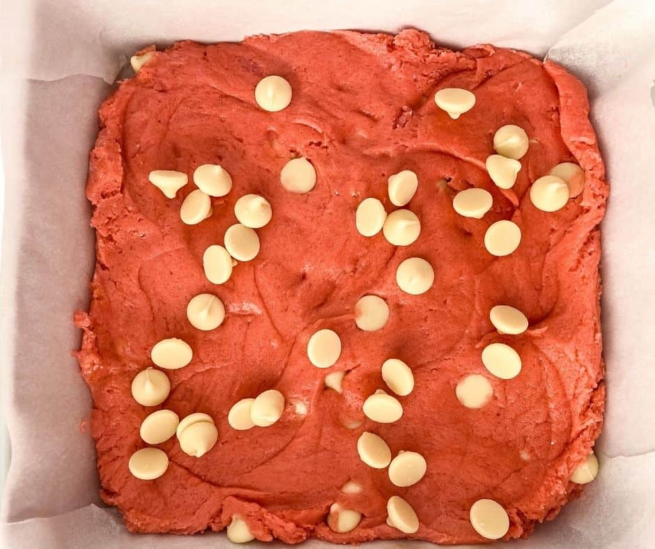 Strawberry blondie batter pressed into a parchment-lined air fryer pan