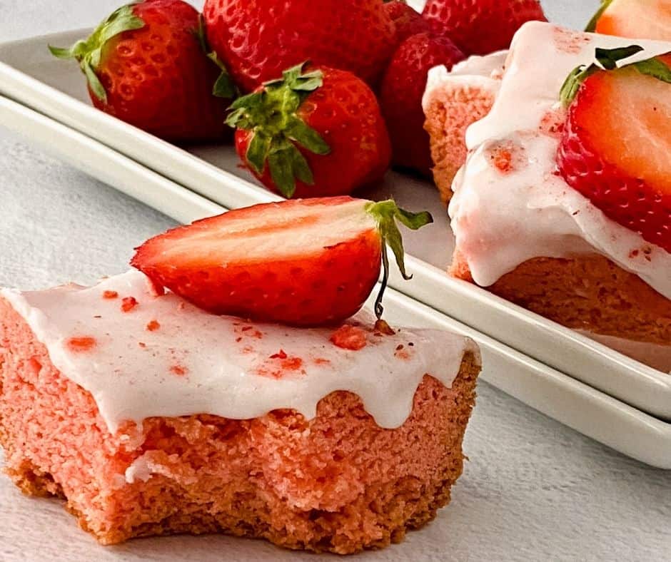 Sliced air fryer strawberry blondies drizzled with vanilla glaze on a board
