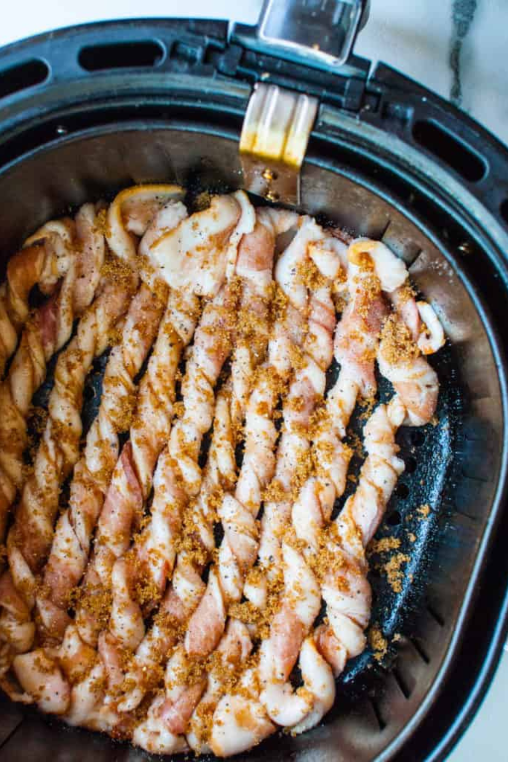 Air Fryer Twisted Candied Bacon cooking in the air fryer basket, showcasing the crispy, caramelized strips as they prepare to become a sweet and savory snack