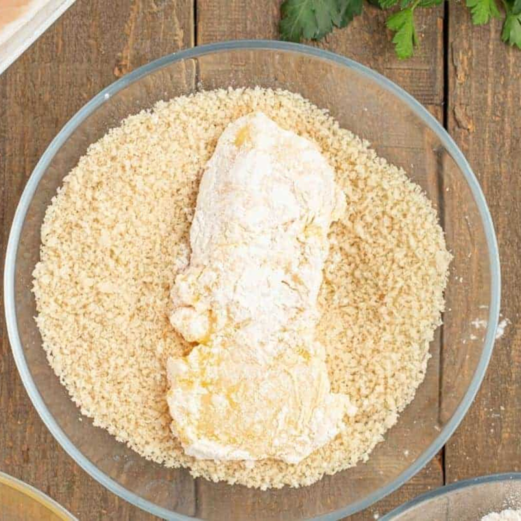 Preparing breaded cod fillets in an air fryer basket with cooking spray for a crispy, golden finish.