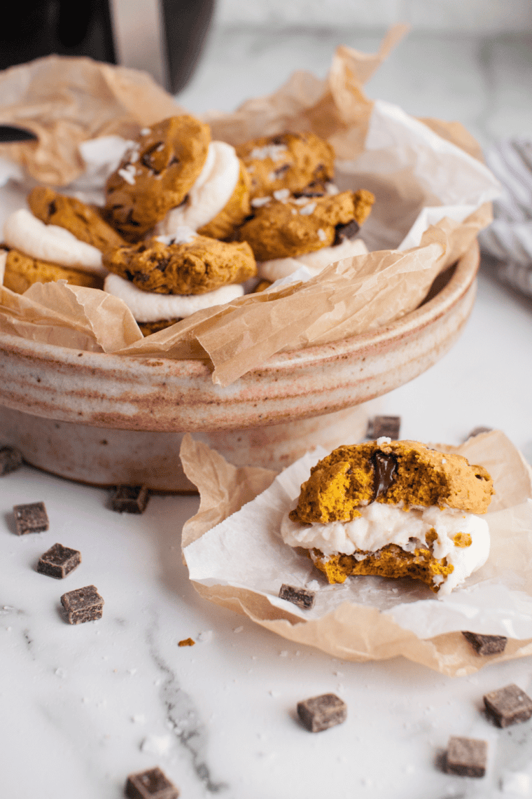 Soft pumpkin chocolate chunk sandwich cookies from the air fryer, filled with creamy frosting and melty chocolate pieces.