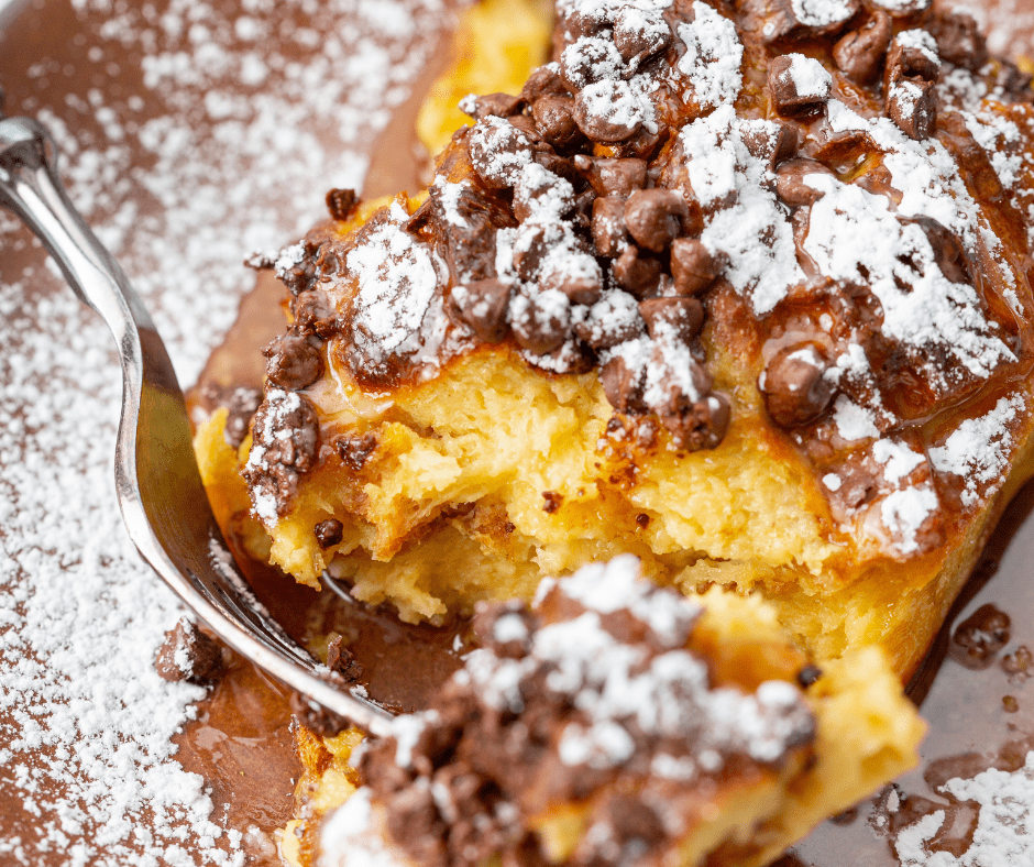 Air fryer chocolate chip French toast casserole with golden baked bread, melty chocolate chips, powdered sugar, and maple syrup on top