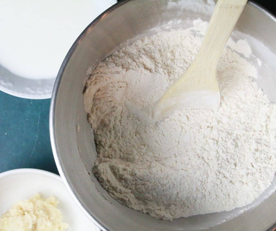 Dough ingredients being mixed in a stand mixer, forming a dough ball, then transferred to a large bowl sprayed with cooking spray, covered with a dish towel to rise for one hour.