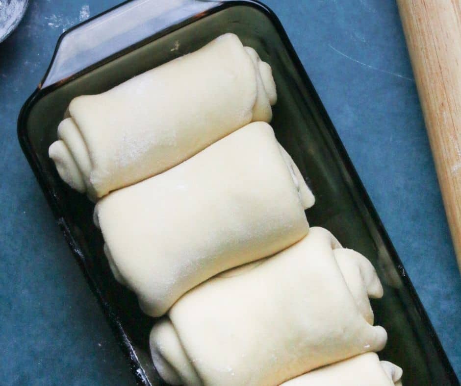 Rolled dough sections placed in the air fryer pan to rise, then brushed with melted butter and air fried at 350°F for 15-20 minutes until golden brown, cooling on a rack before serving.