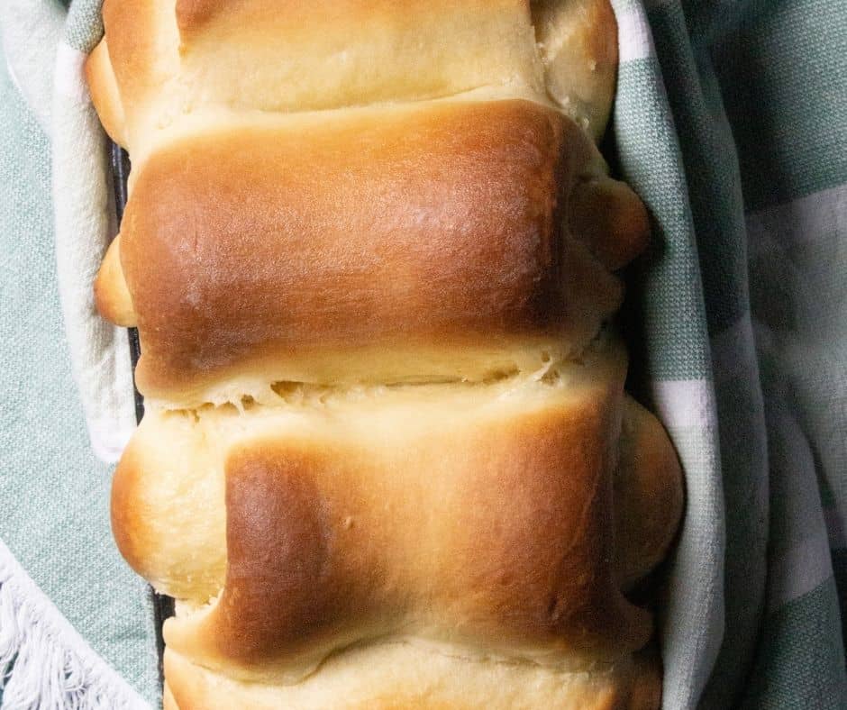 Soft and fluffy Air Fryer Milk Bread loaf, golden-brown and sliced, served on a wooden board with butter.