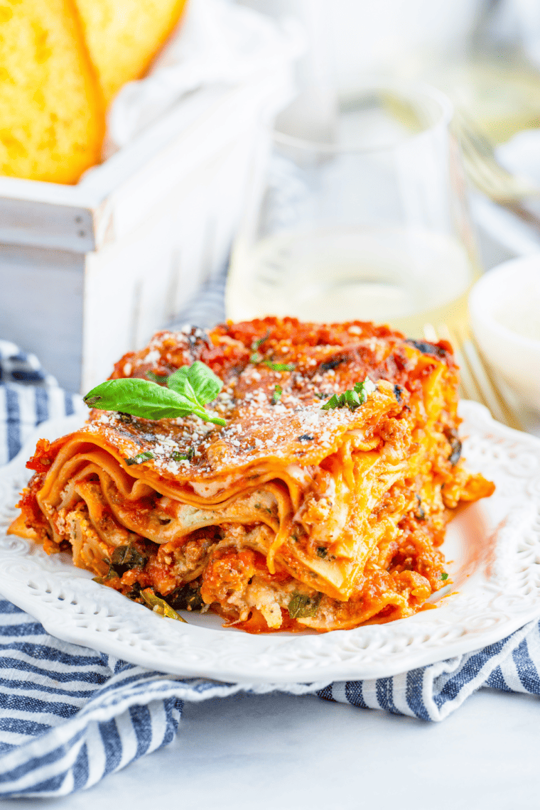 Large slice of air fryer lasagna on a white plate showing distinct layers of pasta, ricotta, sausage, and melted cheese