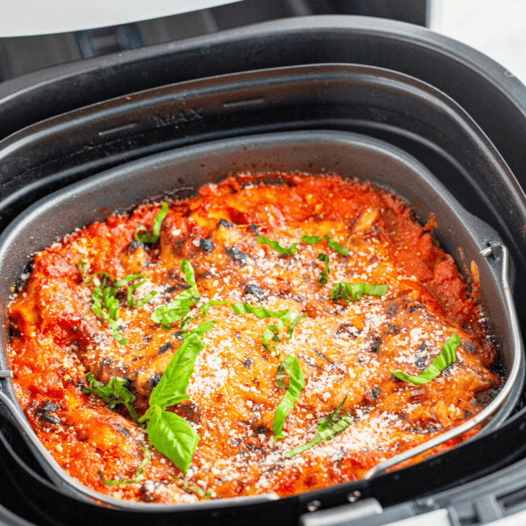 Close up of cooked air fryer lasagna with golden brown bubbly cheese on top, fresh from the air fryer basket