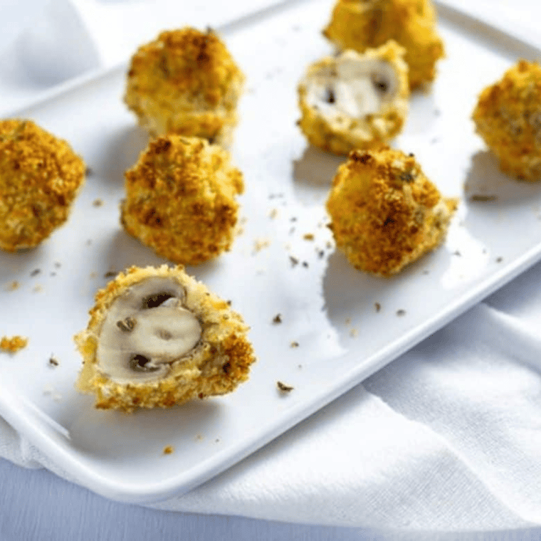 Plate of crispy fried mushrooms with golden coating, seasoned with onion powder, garlic powder, and Parmesan cheese.