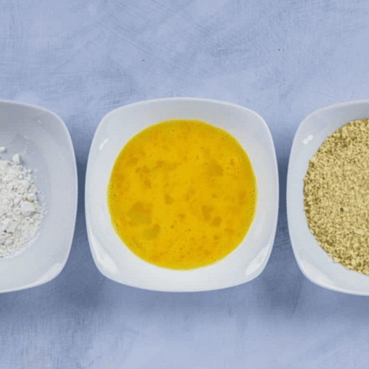 Set up a breading station with flour, beaten eggs, and breadcrumb mixture in three separate bowls.