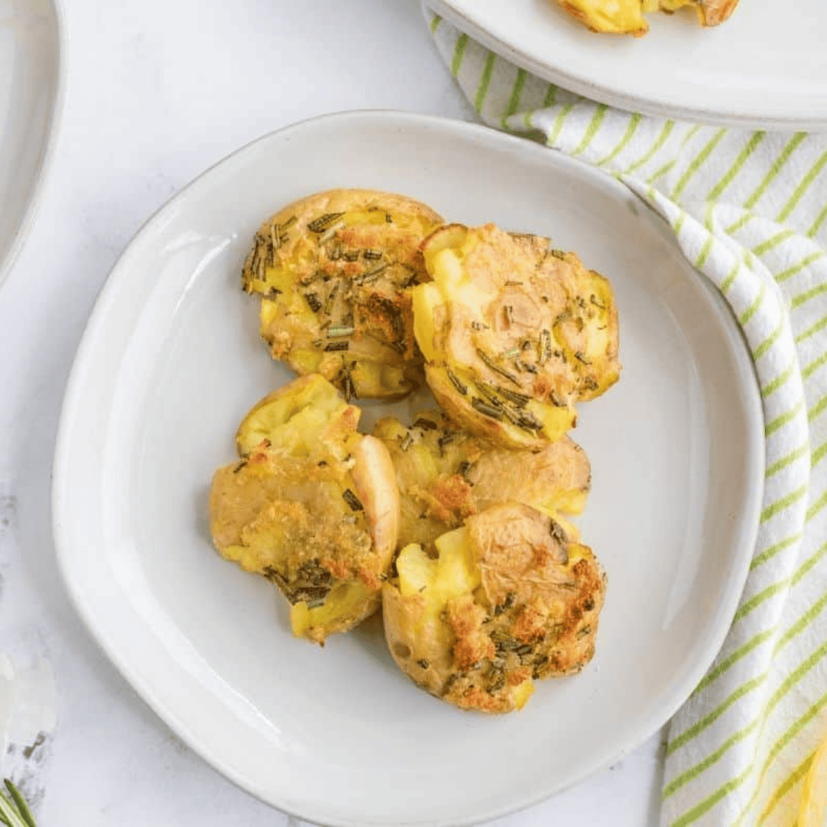 Crispy golden fried smashed potatoes on a plate, garnished with fresh herbs.