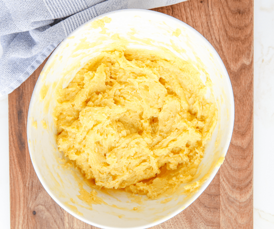Removing dough from the pan to cool, then adding eggs one at a time until the mixture becomes shiny.