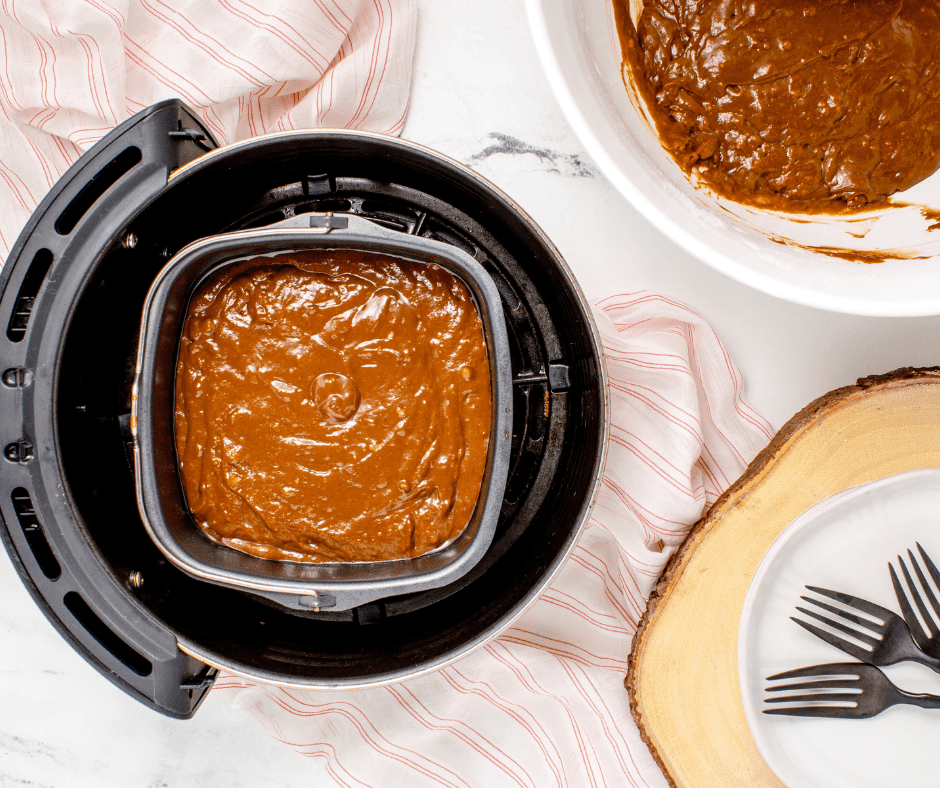 Placing the pan into the air fryer, setting the temperature to 320°F, and adjusting the cook time to 20 minutes for gingerbread cake.