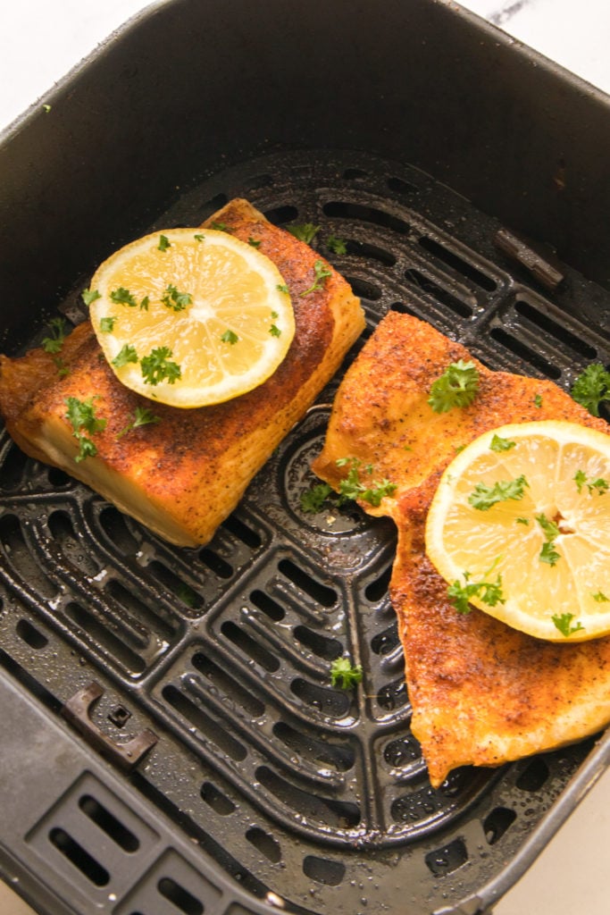 Air fryer halibut fillets, seasoned and cooked to a crispy golden perfection, ready to serve.