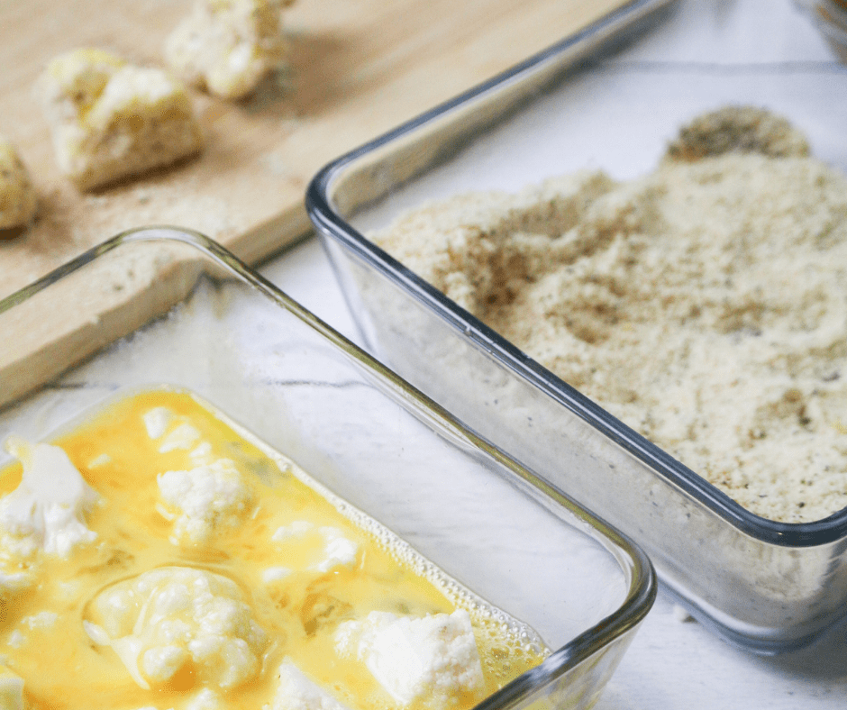 Placing breaded cauliflower florets in a single layer in the air fryer basket and cooking until golden and crispy.