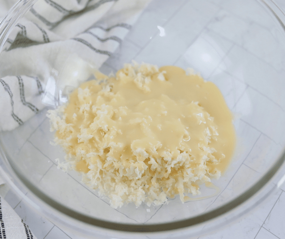 Combine unsweetened coconut flakes and sweetened condensed milk in a bowl.