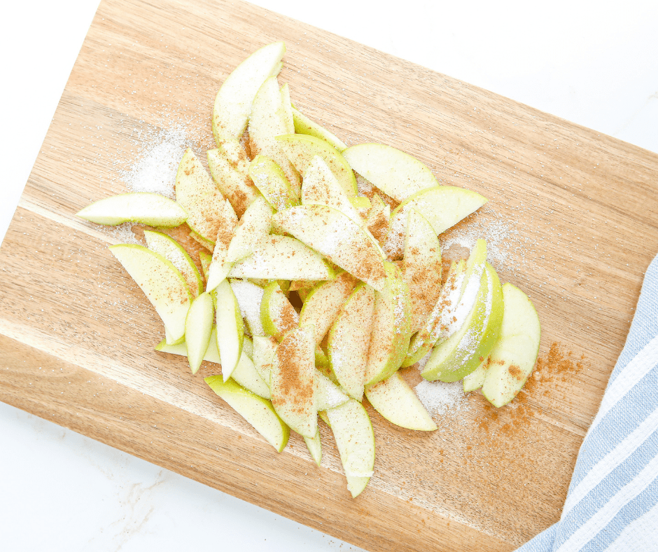 Sliced apples tossed with cinnamon and sugar in a bowl