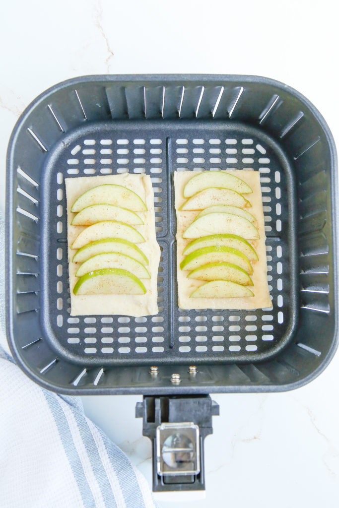 Assembled apple tarts arranged in the air fryer basket before cooking