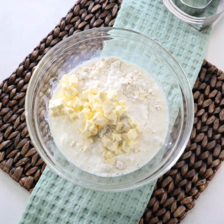  Mixing flour, baking powder, salt, sugar, and butter into a crumbly texture before adding buttermilk to form biscuit dough.
