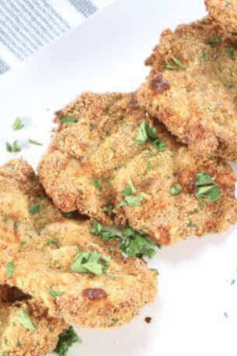 Air fryer chicken thigh schnitzel plated with lemon and fresh parsley
