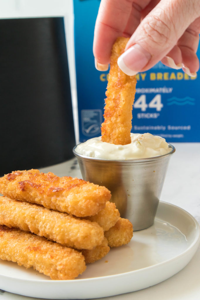 Air Fryer Frozen Fish Sticks being dunked in sauce