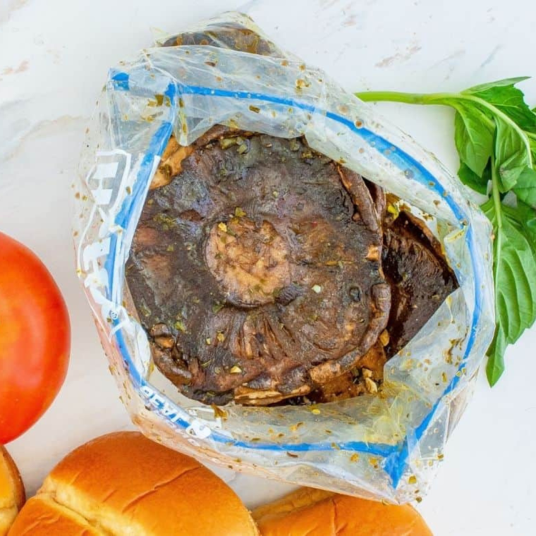 Portobello mushrooms being marinated in a garlic and herb mixture, preparing them for the air fryer.