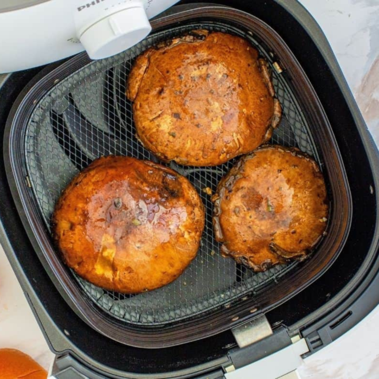 Portobello mushrooms placed in the air fryer basket, ready to be cooked.