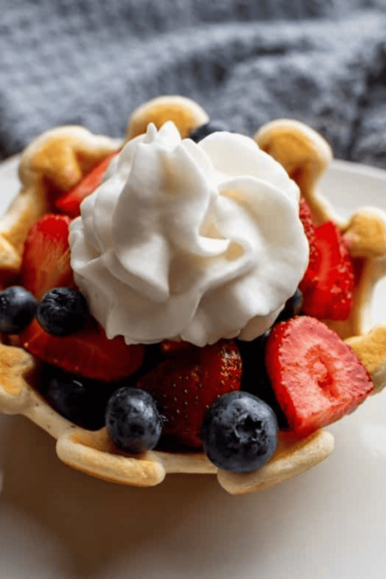 Golden crispy waffle bowl made in the air fryer filled with scoops of ice cream and toppings.