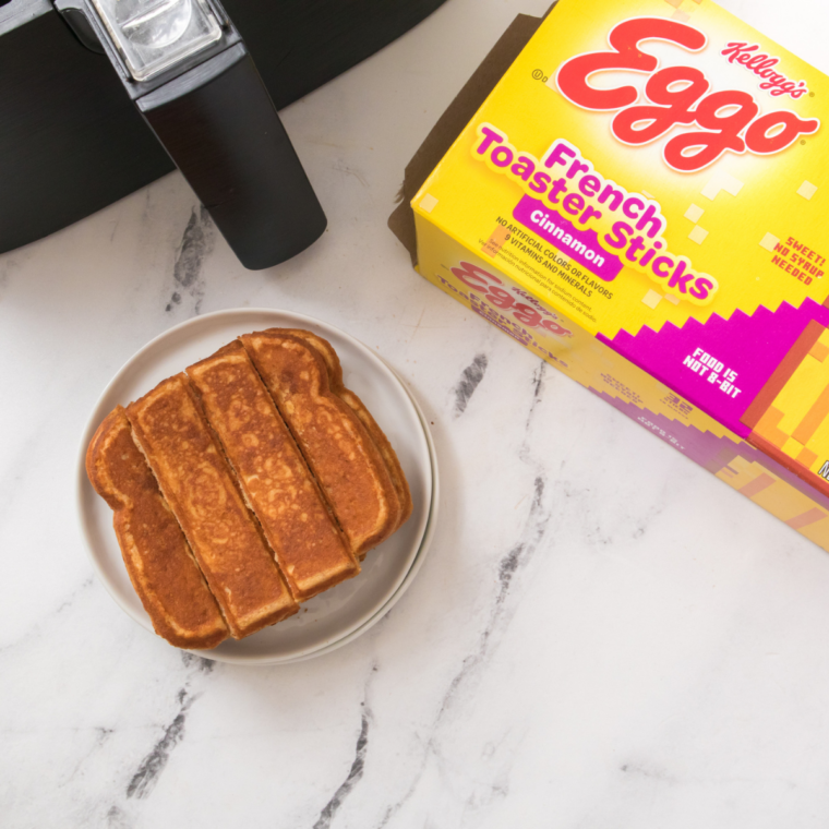 Box of Eggo French Toast Sticks on a marble counter with a bottle of maple syrup