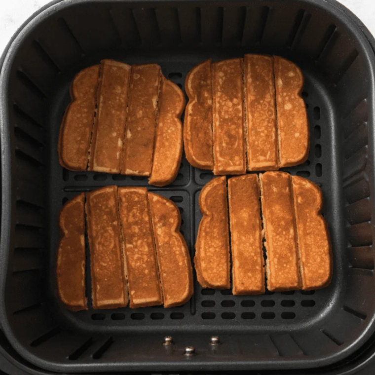 Frozen Eggo French Toast Sticks arranged in a single layer with space between them in an air fryer basket