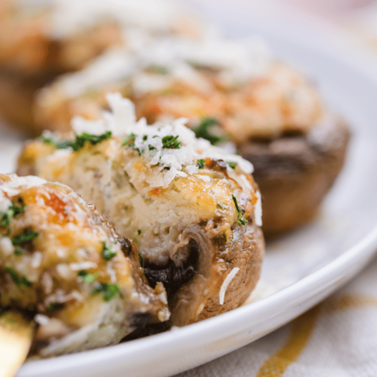 Golden-brown air fryer crab stuffed mushrooms filled with a creamy crab mixture, garnished with fresh herbs on a serving plate.