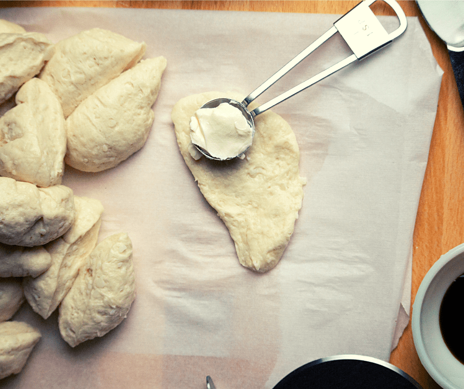 Spreading cream cheese on mini bagels for a rich and creamy filling
