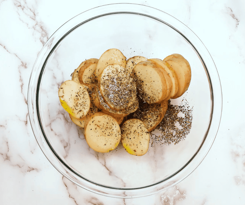 Seasoning Potatoes: Potatoes being tossed in a bowl with olive oil, salt, and pepper.