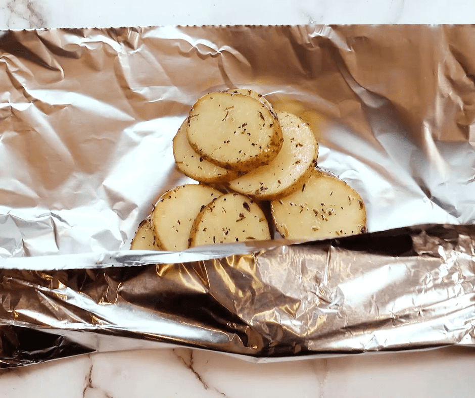 Assembling Foil Packs: Potatoes and toppings placed on foil sheets, ready to be wrapped into foil packs.