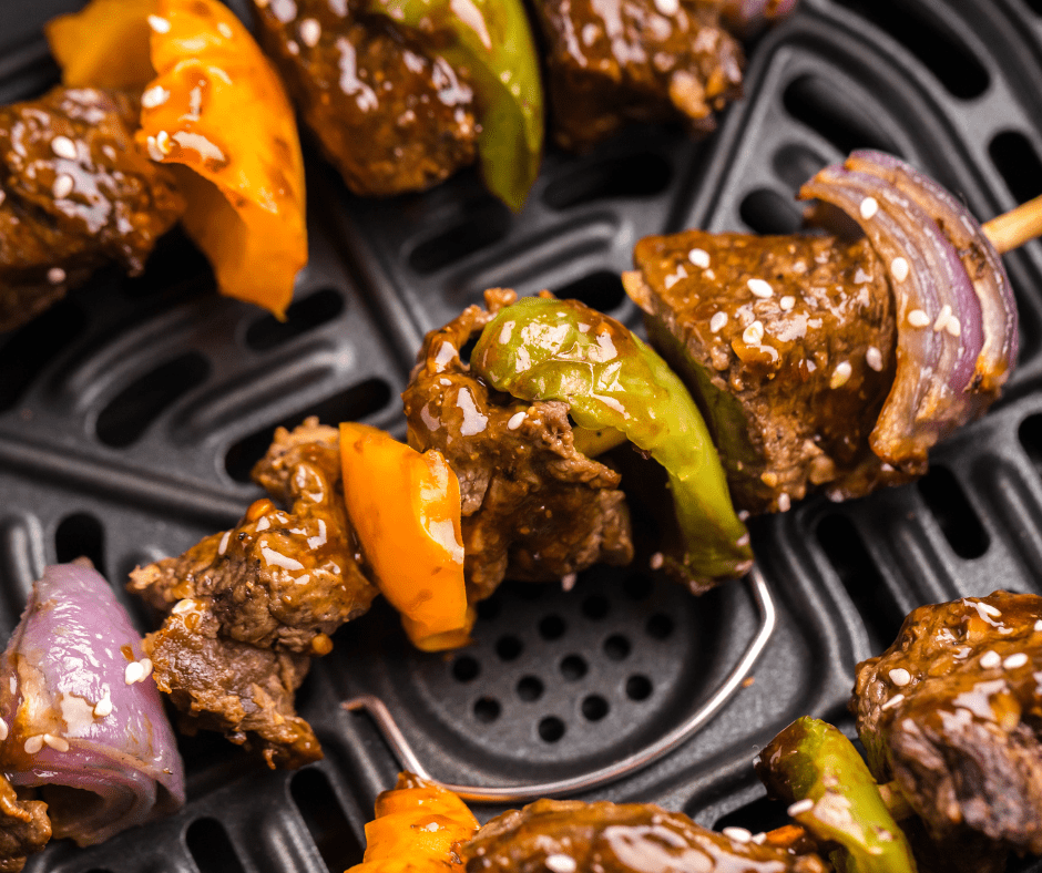 Close up of a beef steak kabob with teriyaki sauce on it, on the bottom of an air fryer basket.