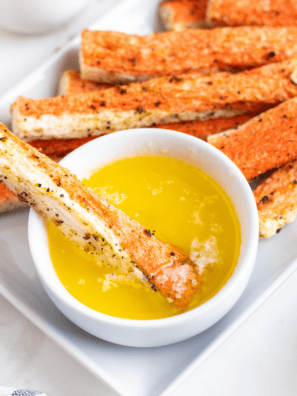 Golden crispy air fryer crab bites on a white plate with garlic butter dipping sauce