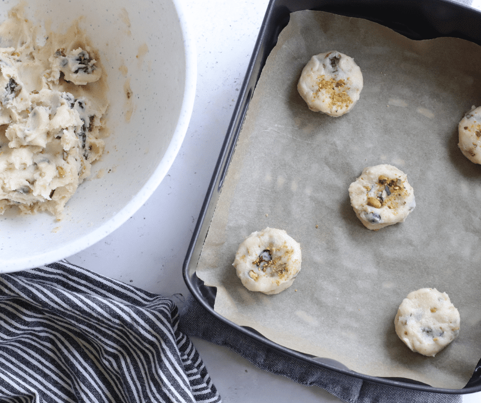 Cranberry pistachio cookie dough rolled into balls on parchment, air frying until golden brown, then cooling on a wire rack.