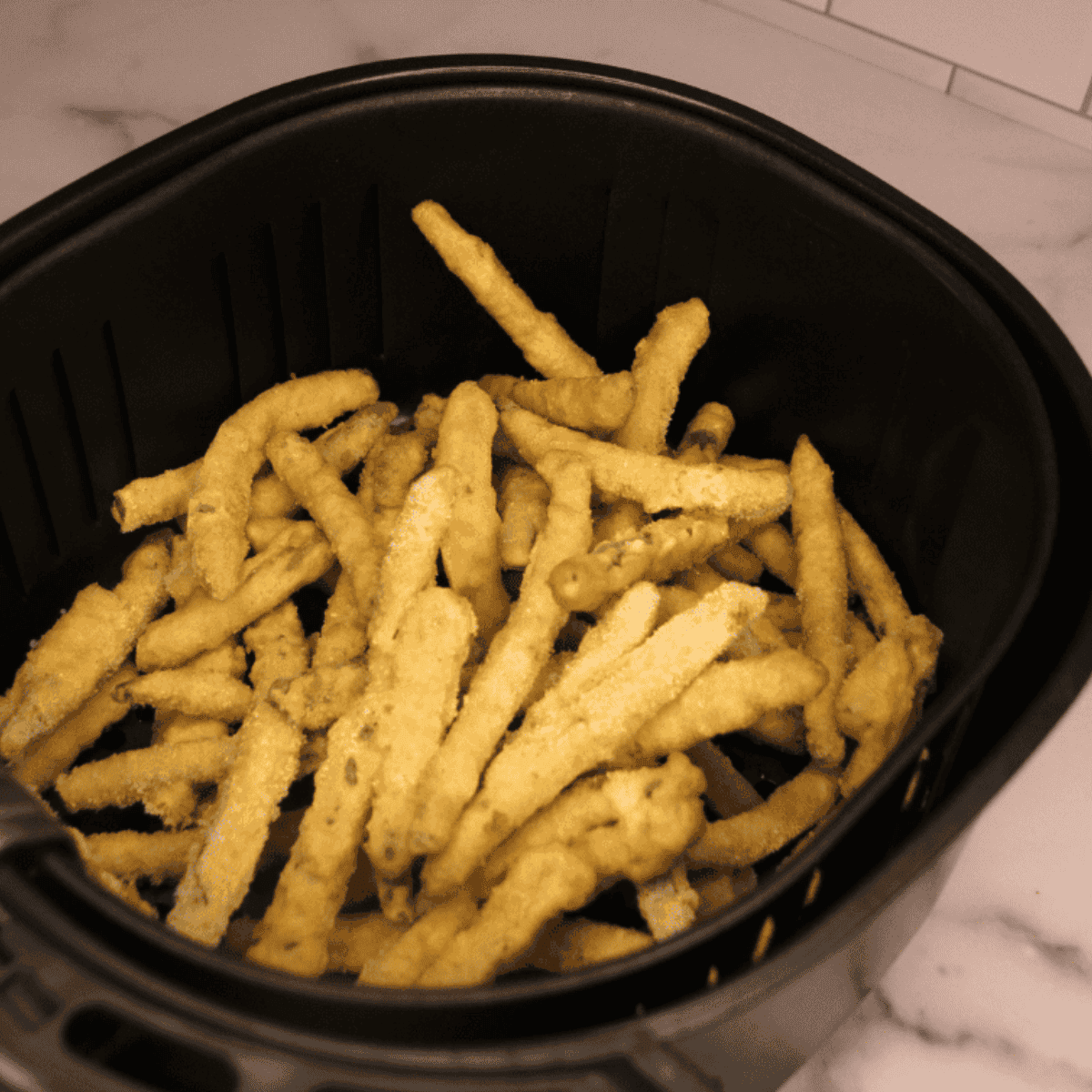 Frozen Breaded Green Beans in the air fryer basket.