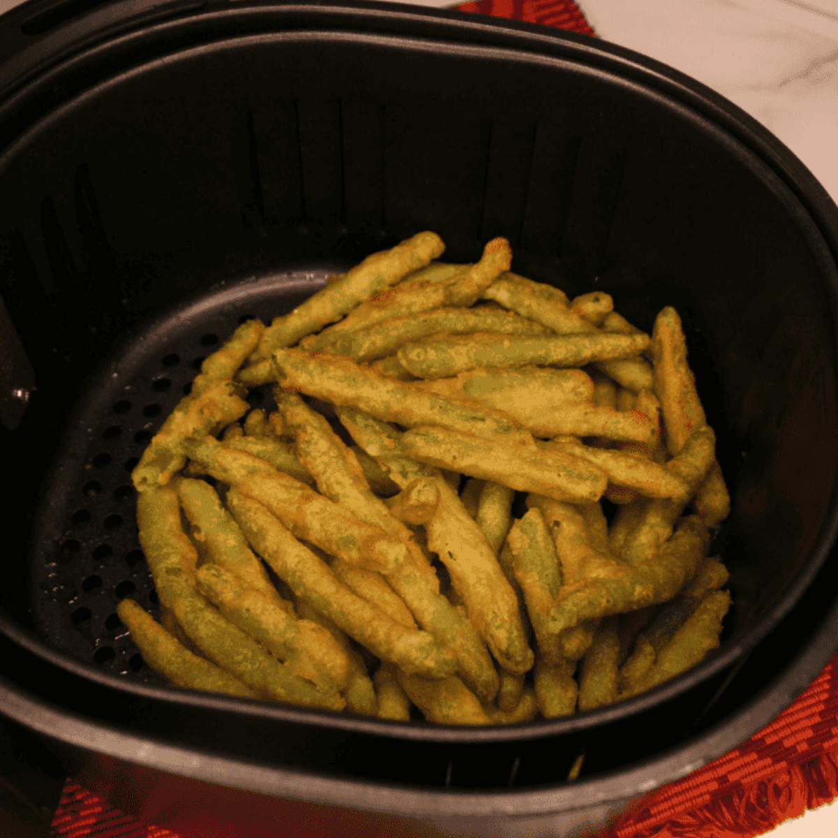Crispy breaded green beans cooked in the air fryer, served hot with a side of dipping sauce.