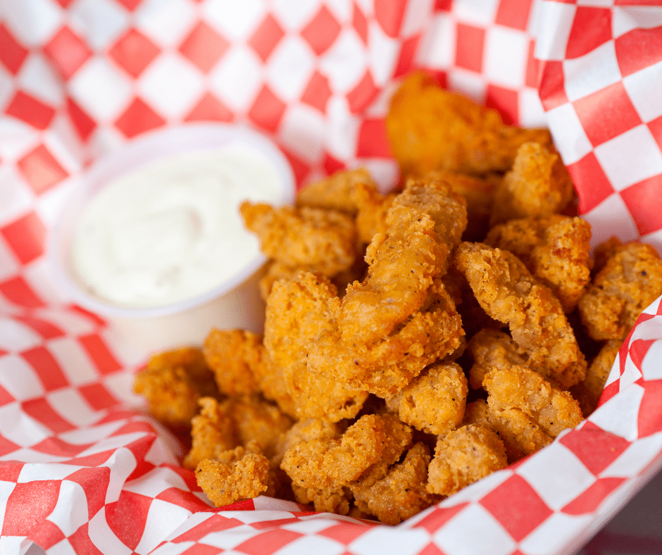 Tyson Any’tizers Popcorn Chicken in a food basket with dipping sauce on the side.