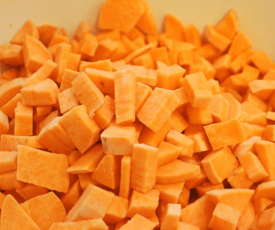 Washing and drying sweet potatoes, then cutting into uniform 1/2 inch cubes.