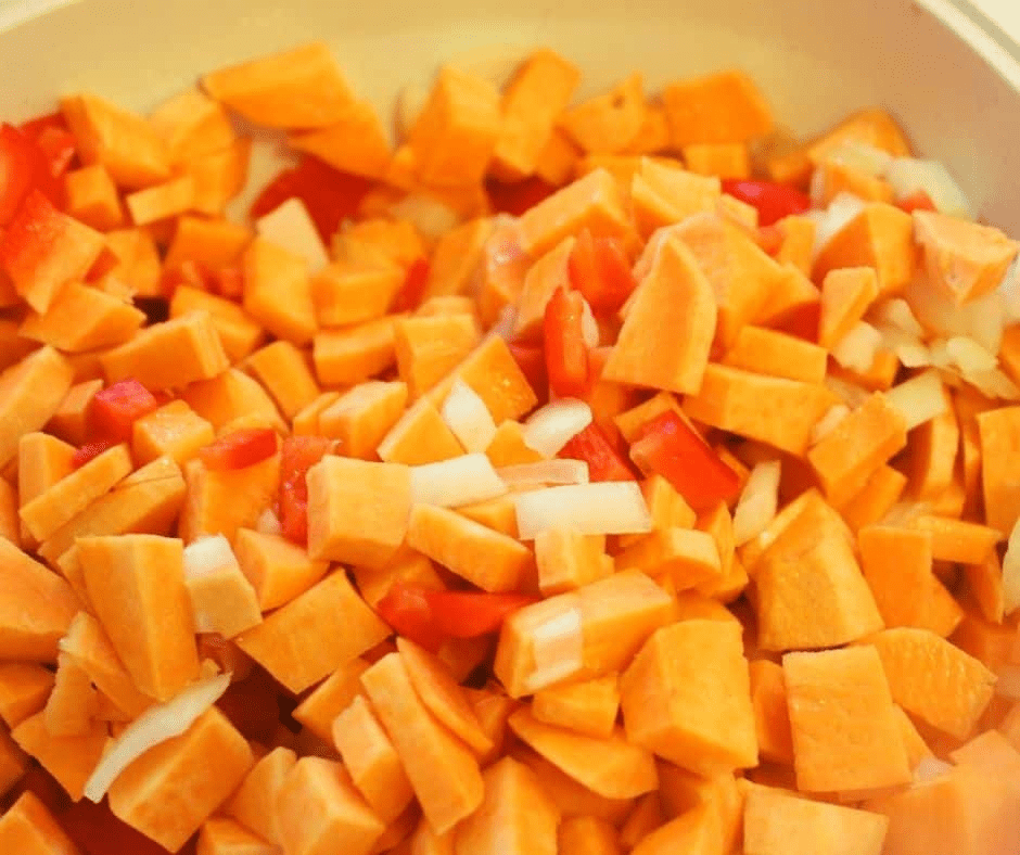 "Cutting onions and bell peppers into 1/2 inch pieces, then mixing with sweet potato chunks in a large bowl."