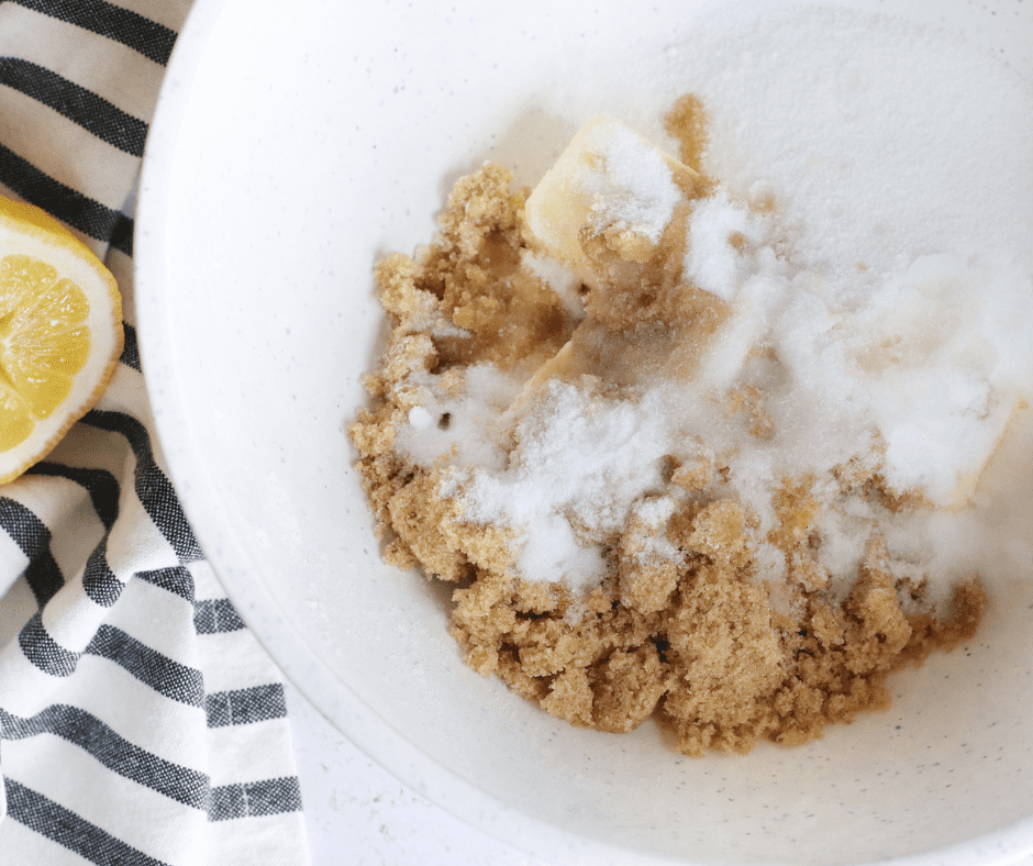 Granulated sugar, brown sugar, and butter being mixed until creamy in a bowl.