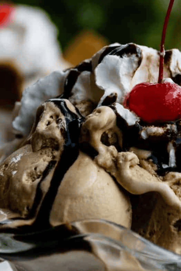 Jar of homemade copycat Hershey’s chocolate syrup with spoon drizzling over ice cream