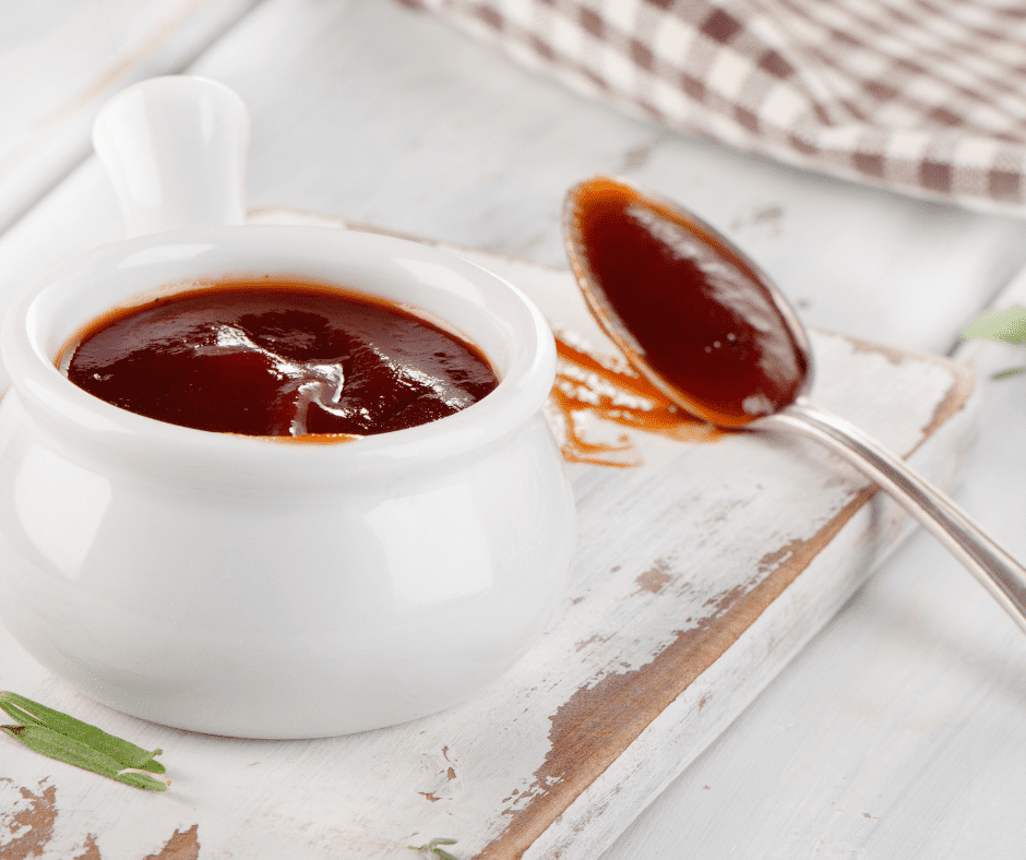Small bowl of homemade McDonald’s BBQ sauce with spoon and nuggets on the side
