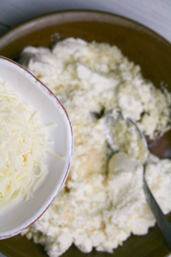Mixing ricotta cheese, breadcrumbs, Romano cheese, parsley, salt, and pepper in a bowl to prepare flavorful meatball mixture.