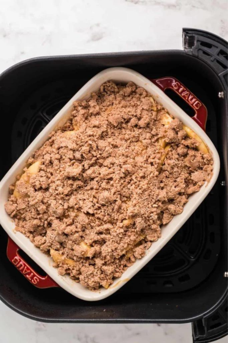 Apple crumble ramekins arranged in an air fryer basket ready to cook