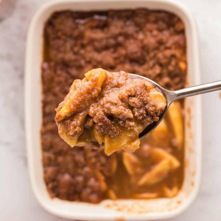 Air fryer amaretto apple crumble in a white ramekin topped with melting vanilla ice cream